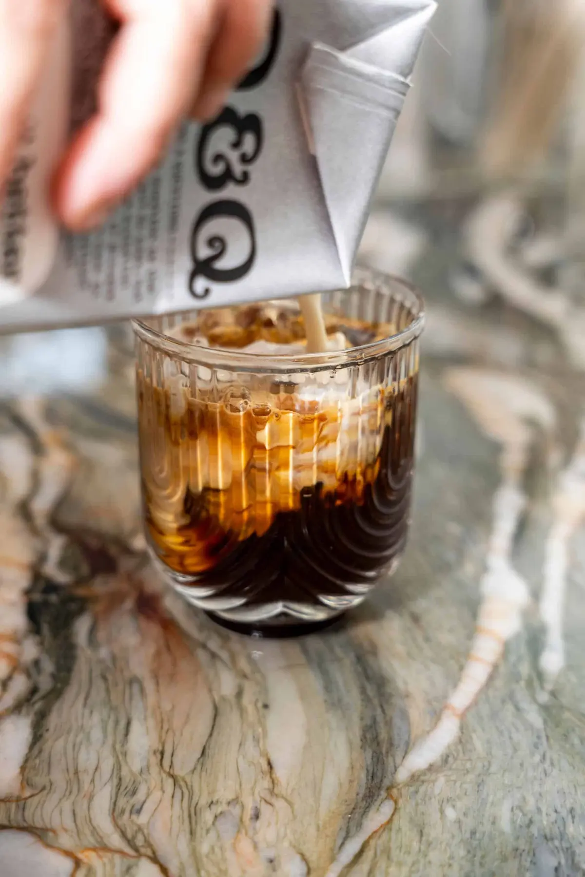 oat milk being poured into a glass of iced espresso at Pour and Decor cafe st pete fl