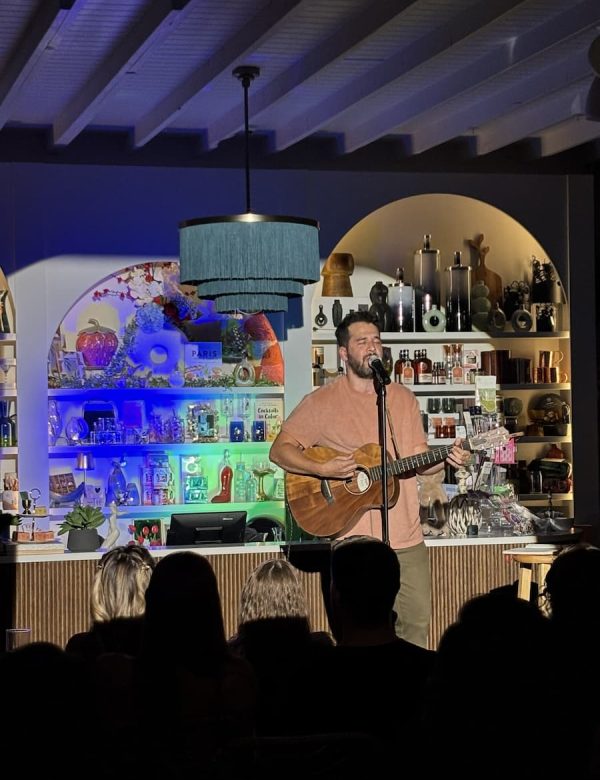 Don't Tell Comedy show hosted at pour and decor in St Pete. Shows a comedian playing his guitar and singing.
